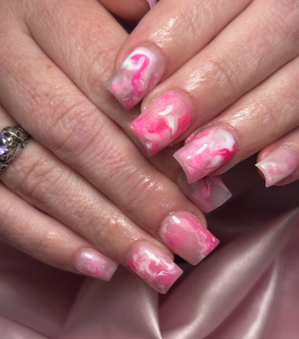 A woman 's nails are painted pink and white with a flamingo design.
