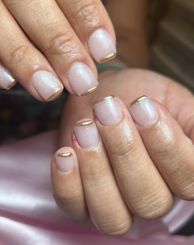 A close up of a woman 's nails with a gold trim.