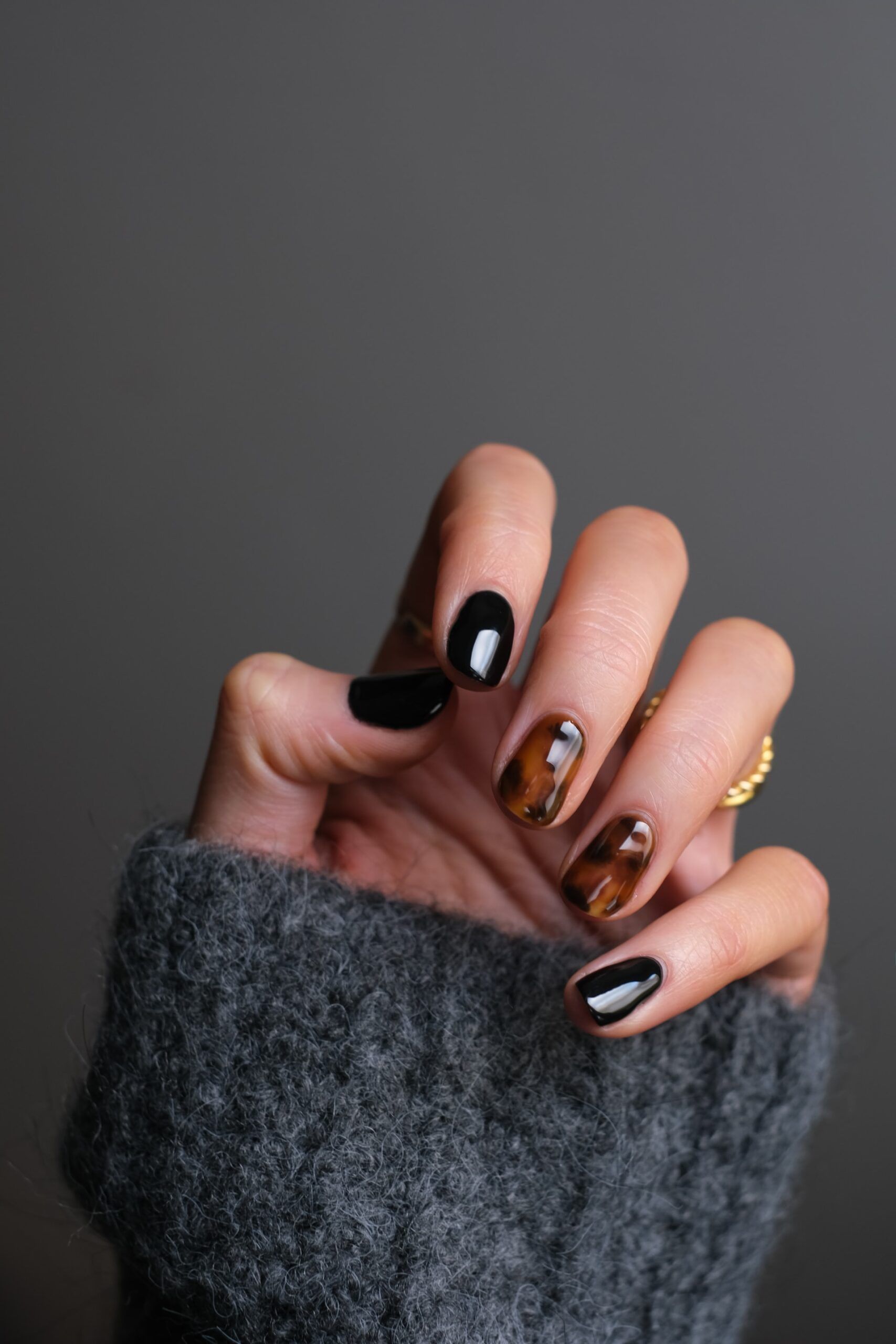 A close up of a person 's hand with black and brown nails.