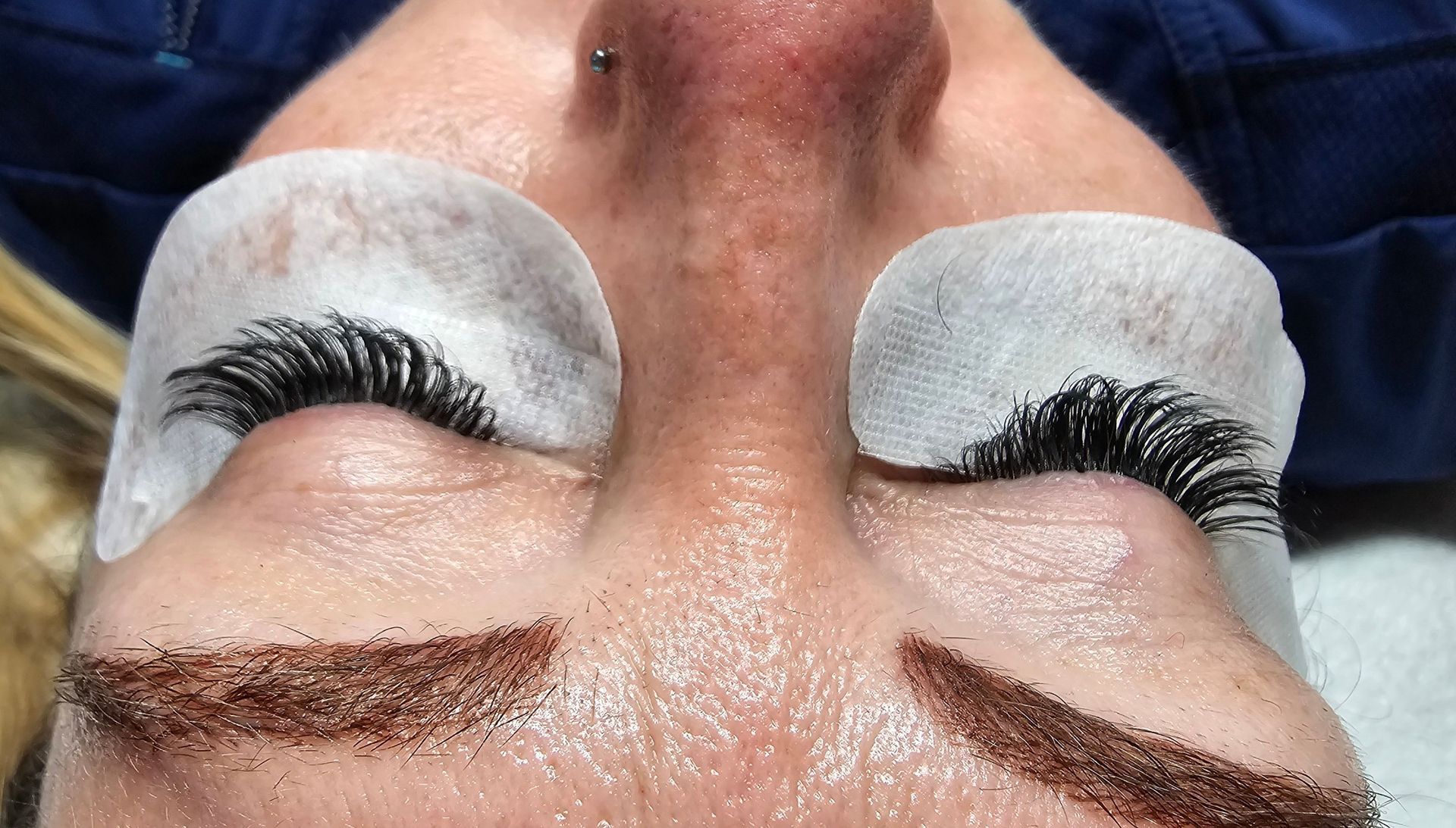 A close up of a woman 's face with false eyelashes and a nose ring.