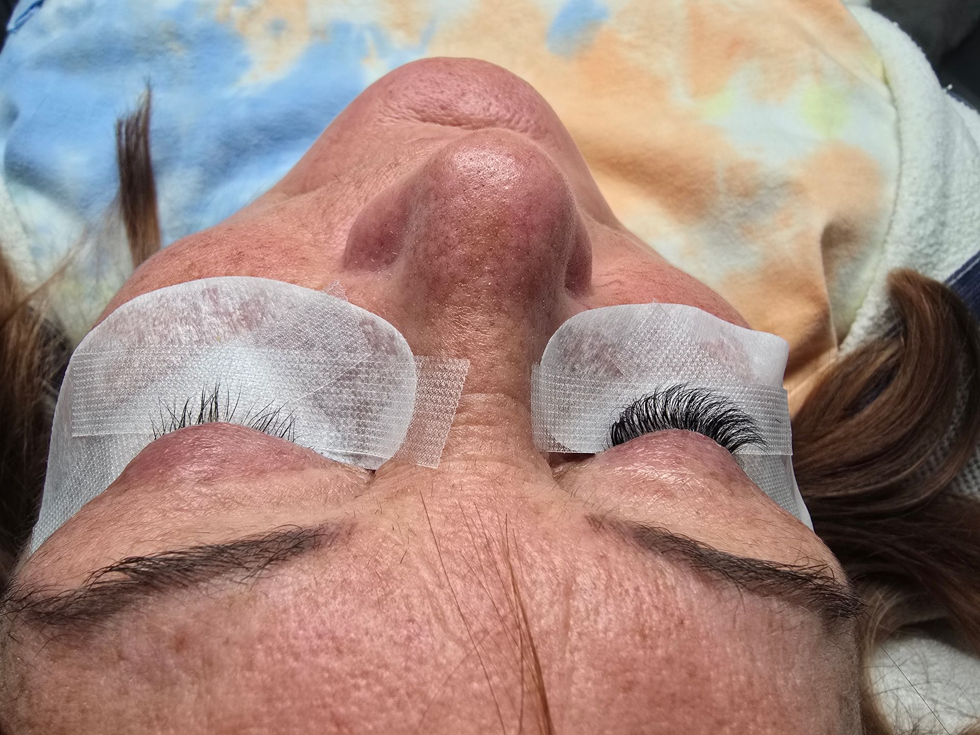 A woman is laying down with a pair of eye patches on her eyes.