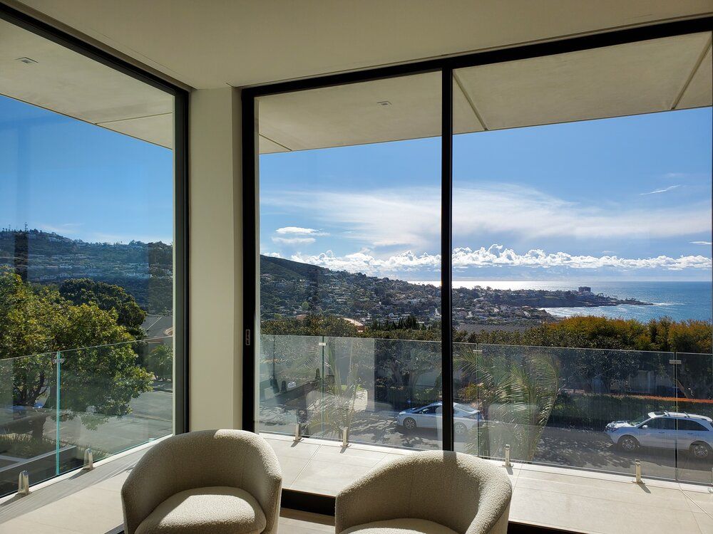 A living room with two chairs and a balcony with a view of the ocean.
