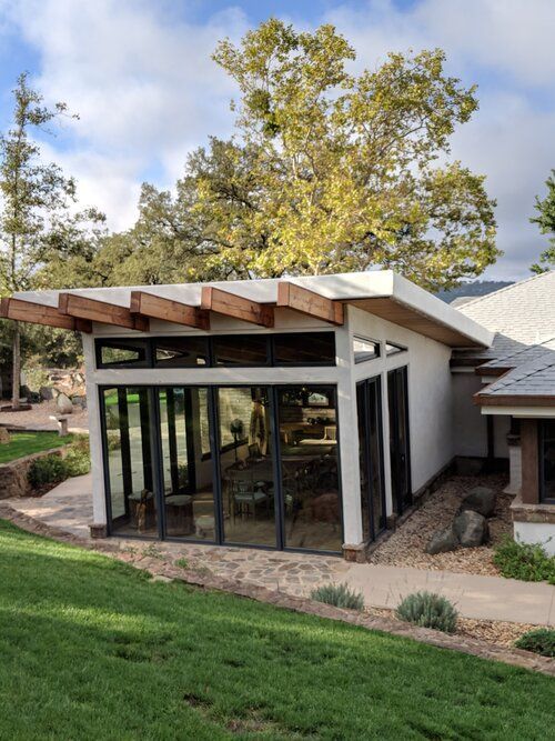 A house with a lot of windows and trees in the background