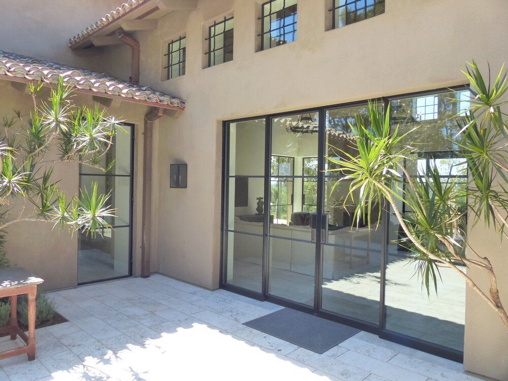 A house with a lot of windows and a patio in front of it.