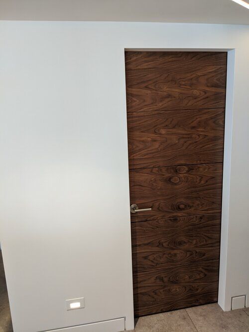 A wooden door is sitting in a room next to a white wall.