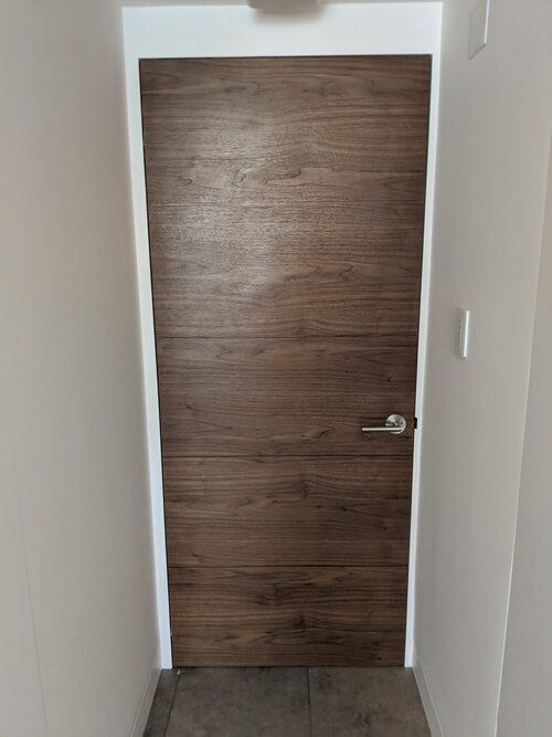 A wooden door is sitting in a hallway next to a wall.