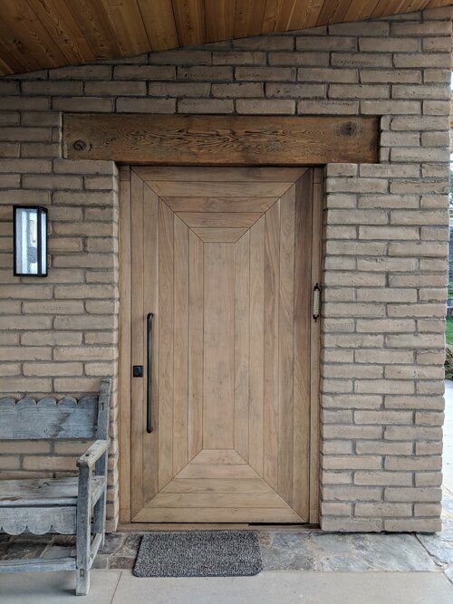 A brick building with a wooden door and a bench