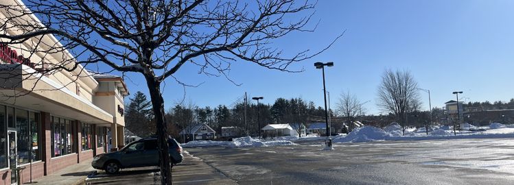 A car is parked in a parking lot in front of a store.
