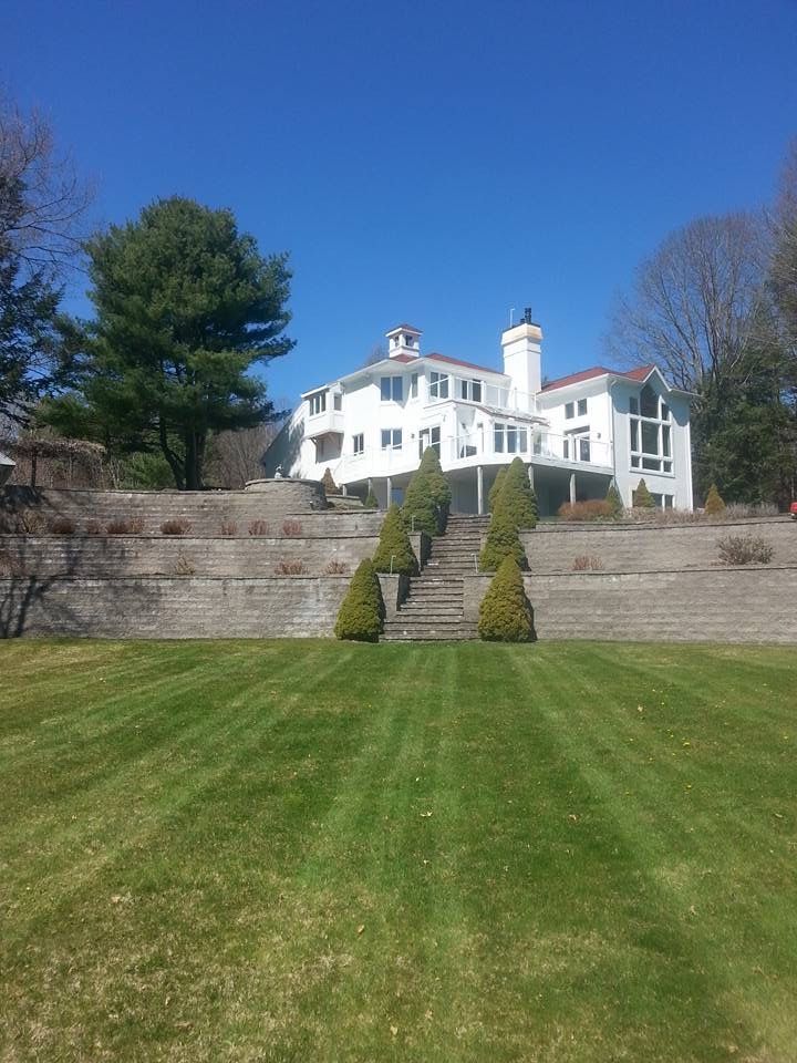 a large white house sits on top of a lush green hillside