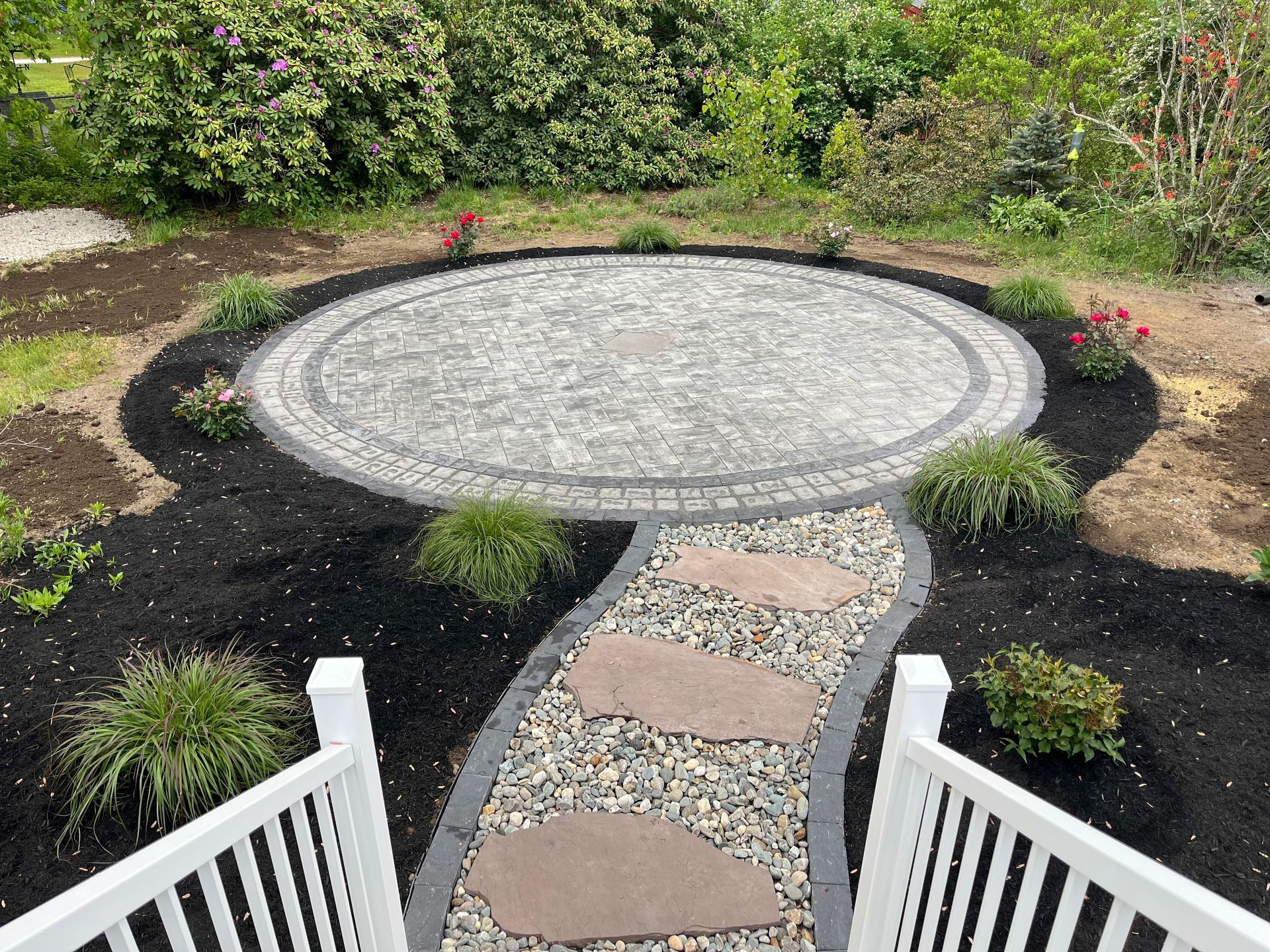 a walkway leading to a circular patio in the middle of a garden
