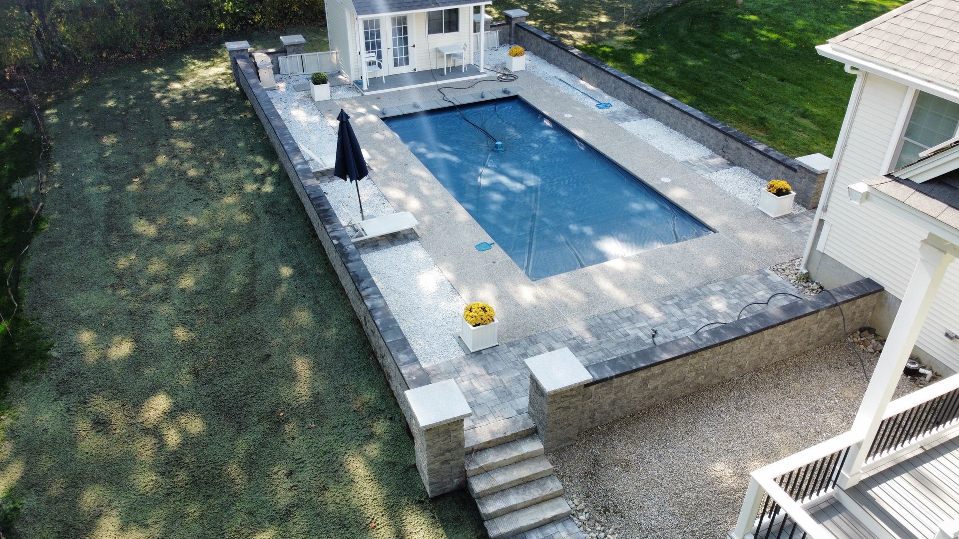 An aerial view of a large swimming pool in the backyard of a house.