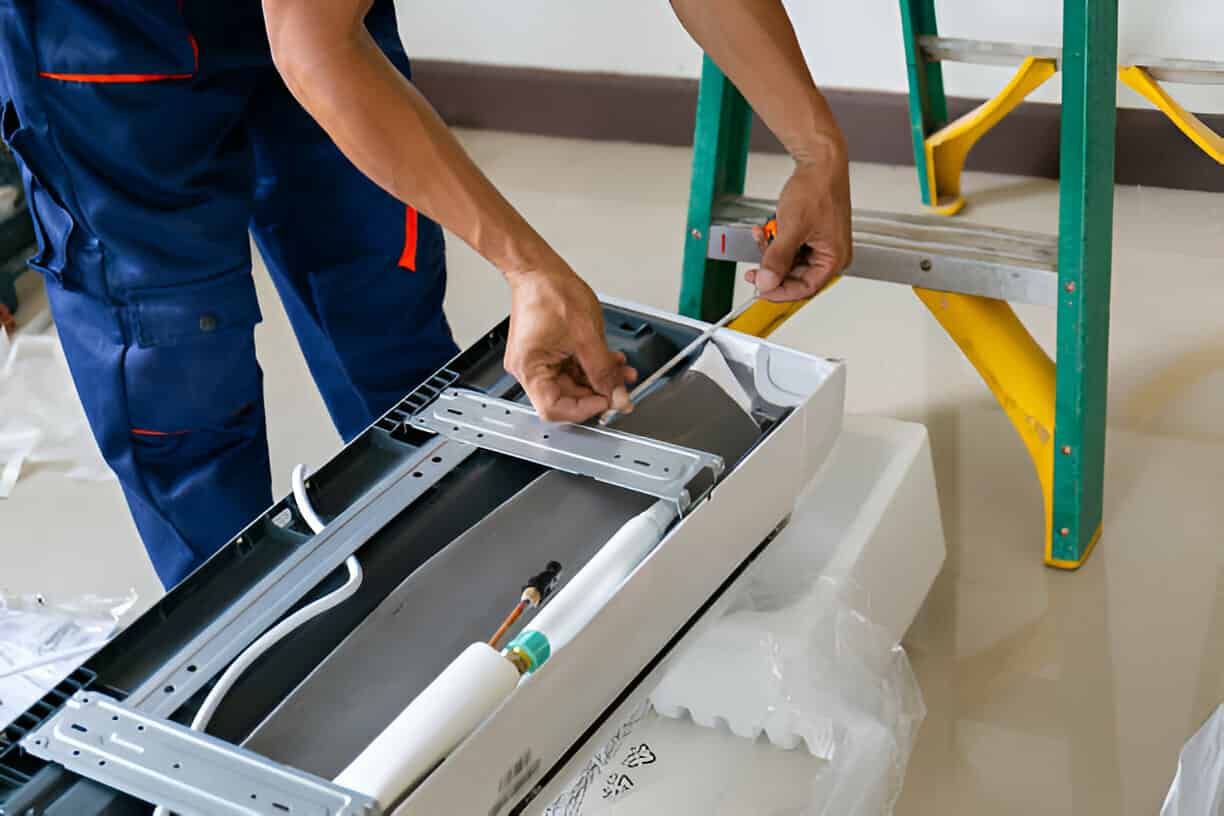 Technician installing parts inside an open electronic device beside a green ladder and yellow stairs