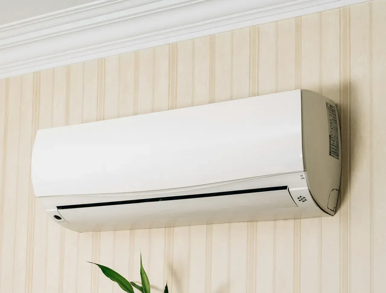 Wall-mounted white air conditioner on a striped wallpapered interior wall