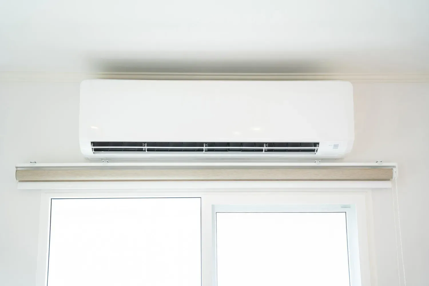 White wall-mounted air conditioner above a window and ledge