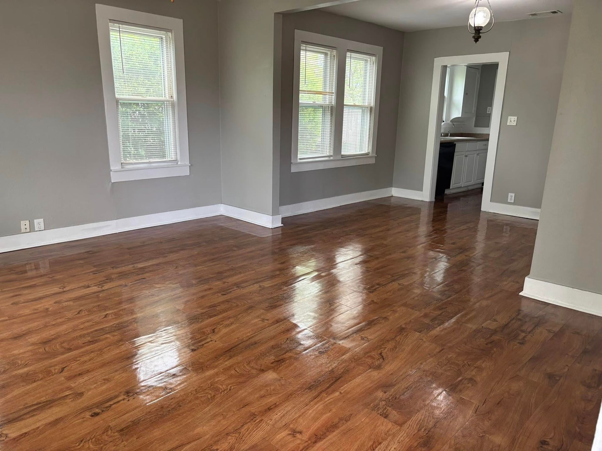 An empty living room with hardwood floors and gray walls.
