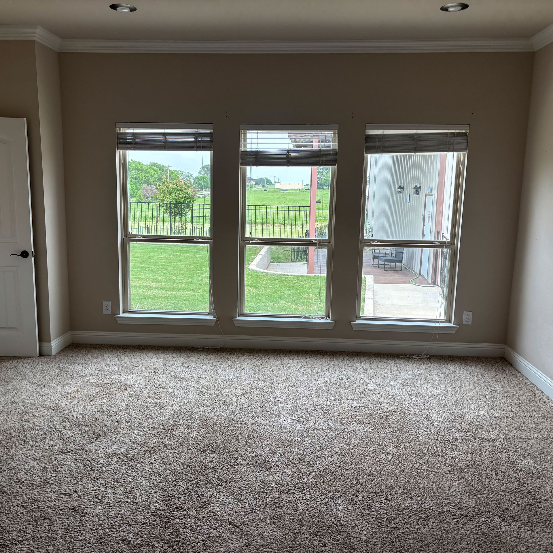 An empty room with three windows and a carpeted floor