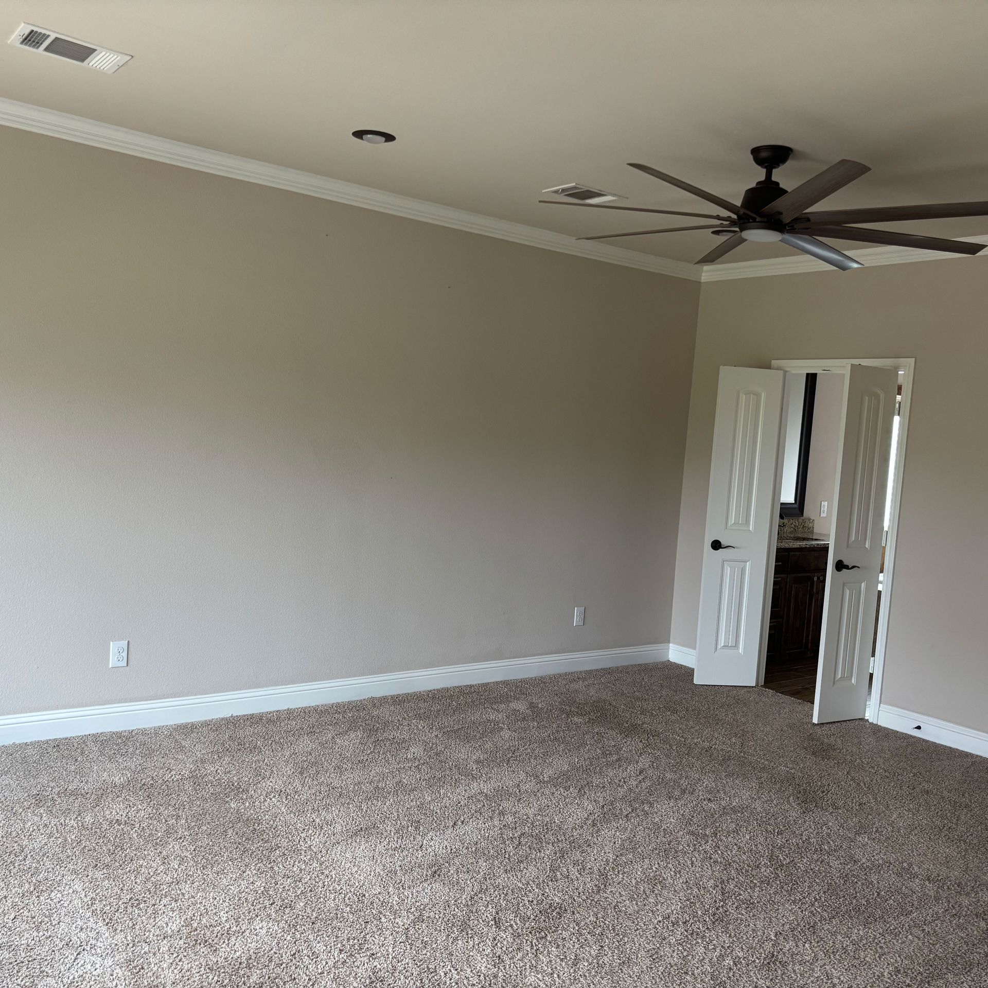 An empty bedroom with a ceiling fan and carpet