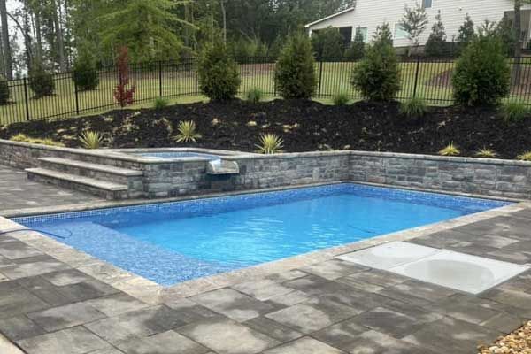 A large swimming pool with a hot tub in the backyard of a house.