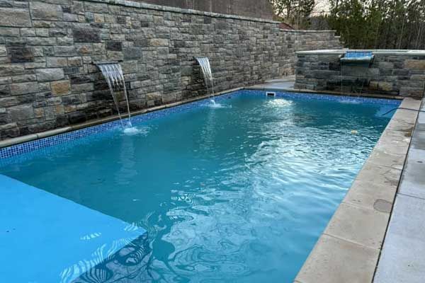 A large swimming pool with a waterfall in the backyard.