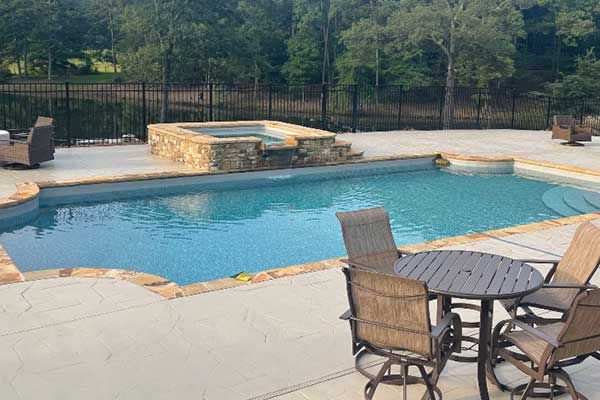 A large swimming pool with a table and chairs in front of it.