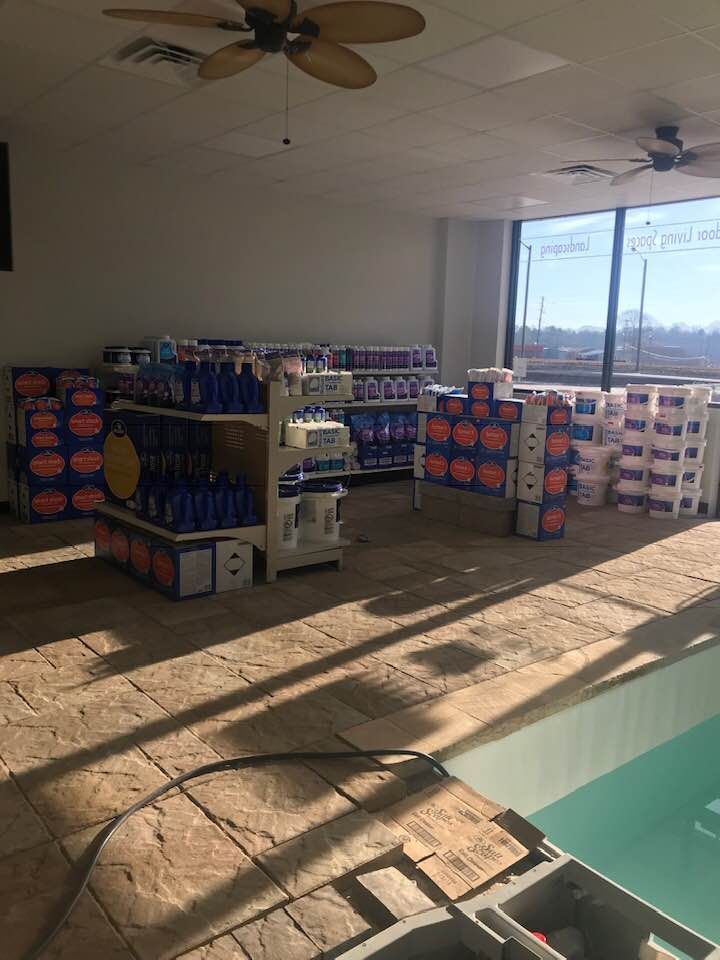 A room with a ceiling fan and a swimming pool in the background.