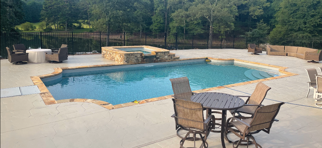 A large swimming pool with a table and chairs in front of it.