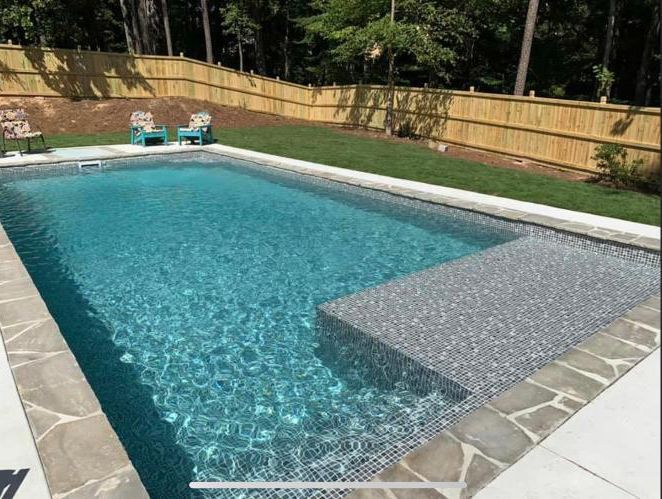 A large swimming pool with a wooden fence surrounding it