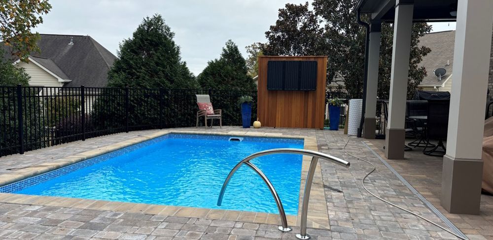 There is a large swimming pool in the backyard of a house.