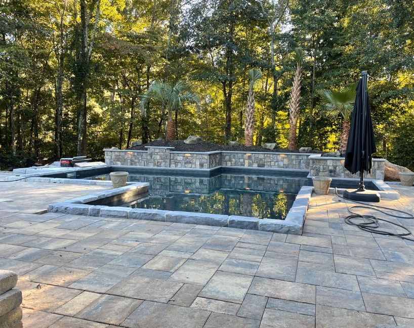 A large swimming pool is surrounded by trees and a patio.