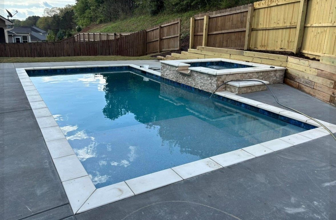 A large swimming pool with a hot tub in the backyard.