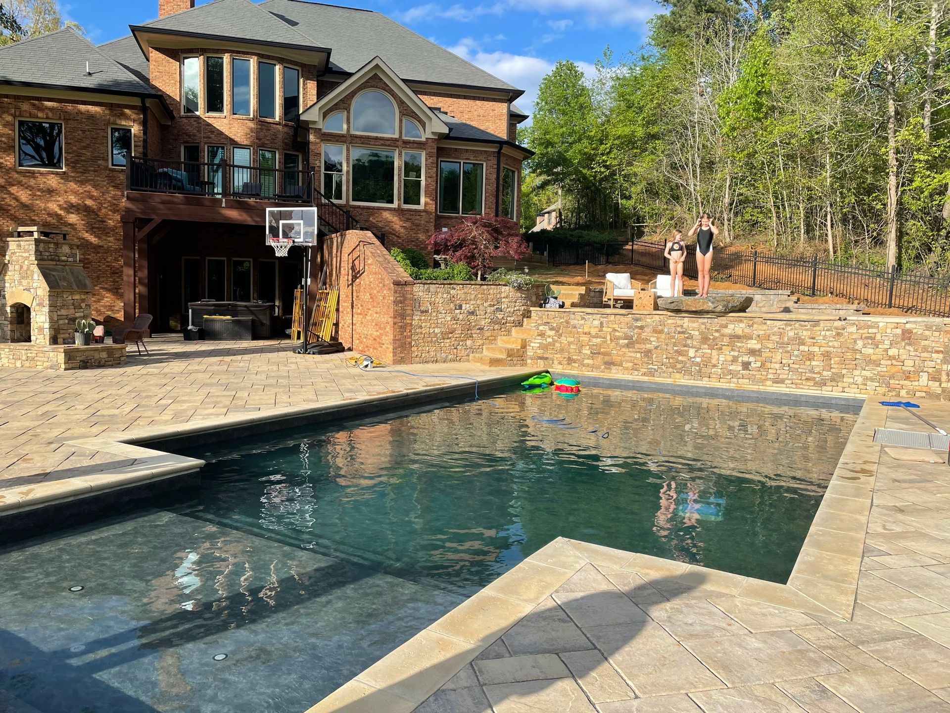 A large brick house with a swimming pool in front of it.