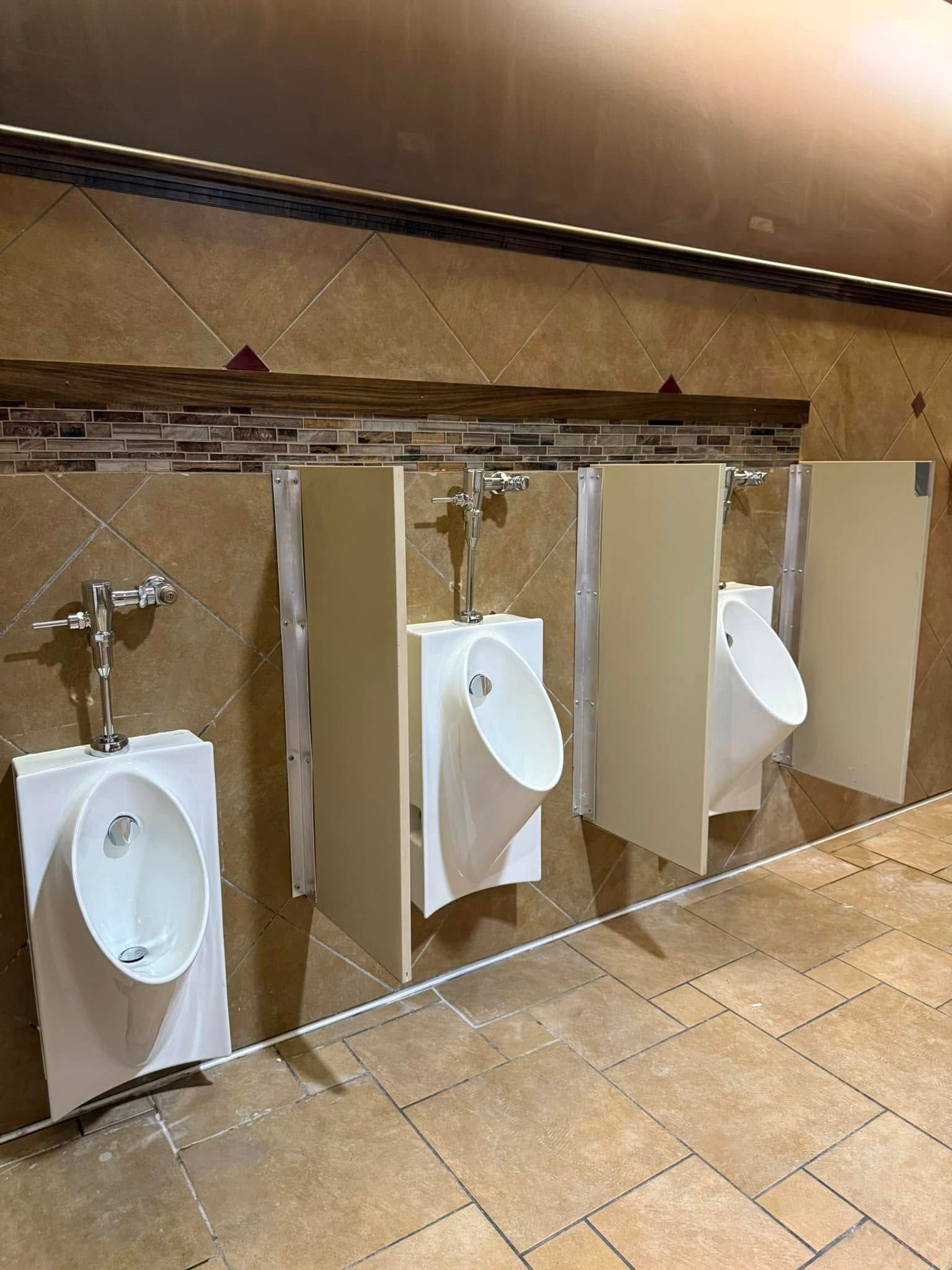 A row of urinals in a public restroom with dividers between them.