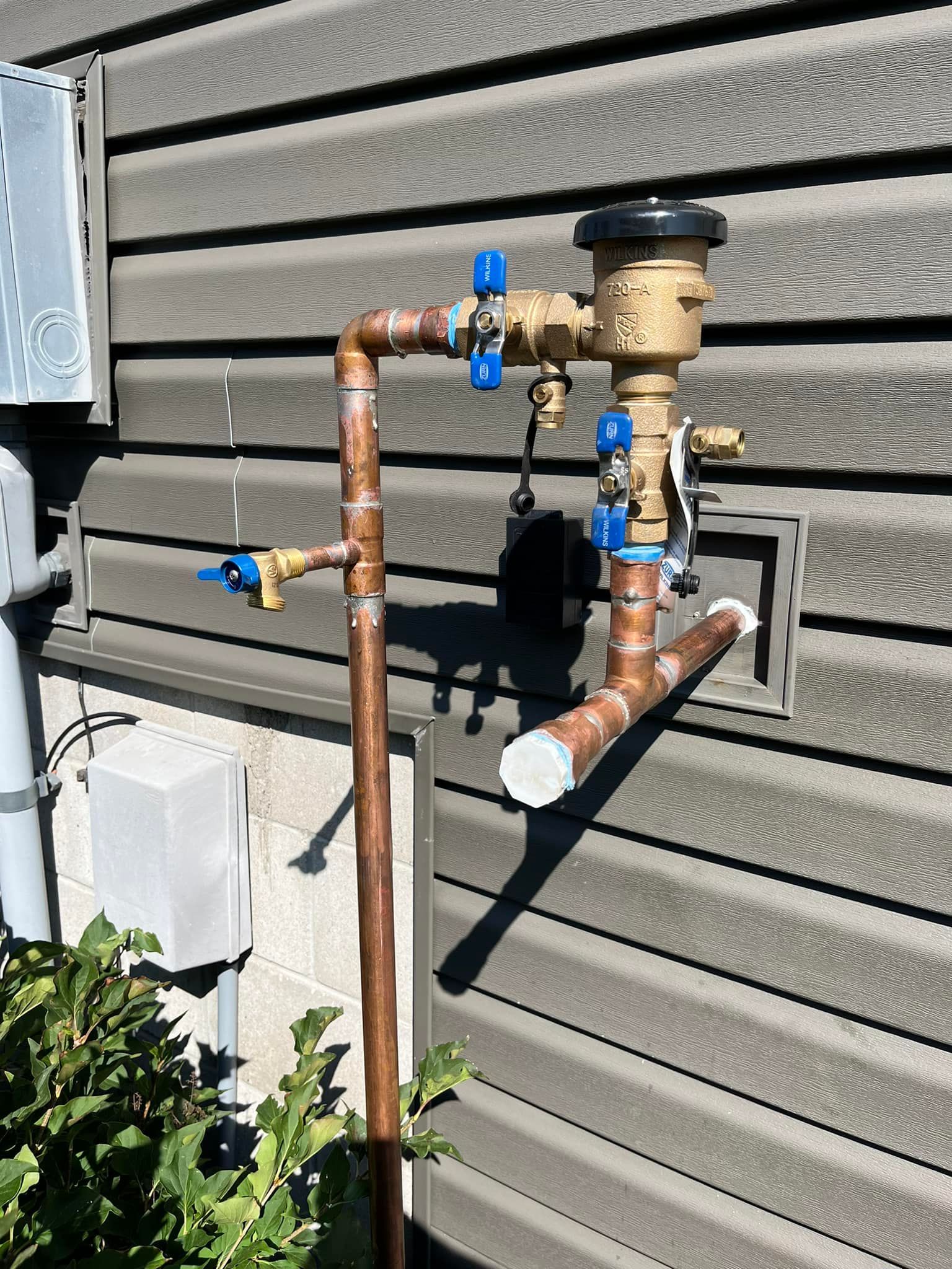 A copper pipe is attached to the side of a house.