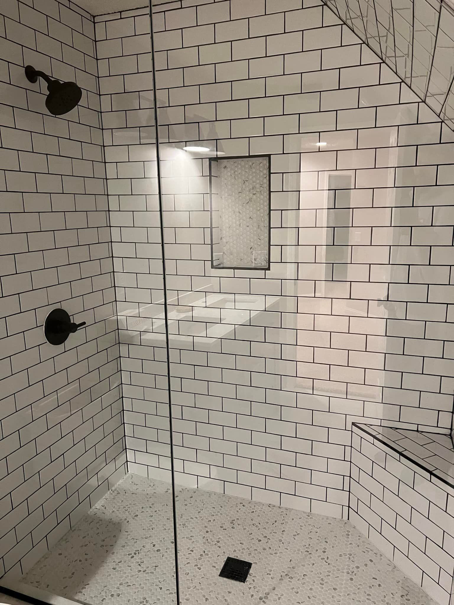 A bathroom with white tiles and a walk in shower.