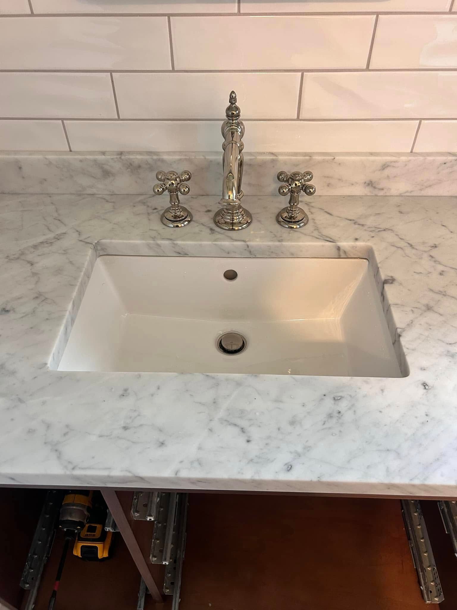 A bathroom sink is sitting on top of a marble counter top.