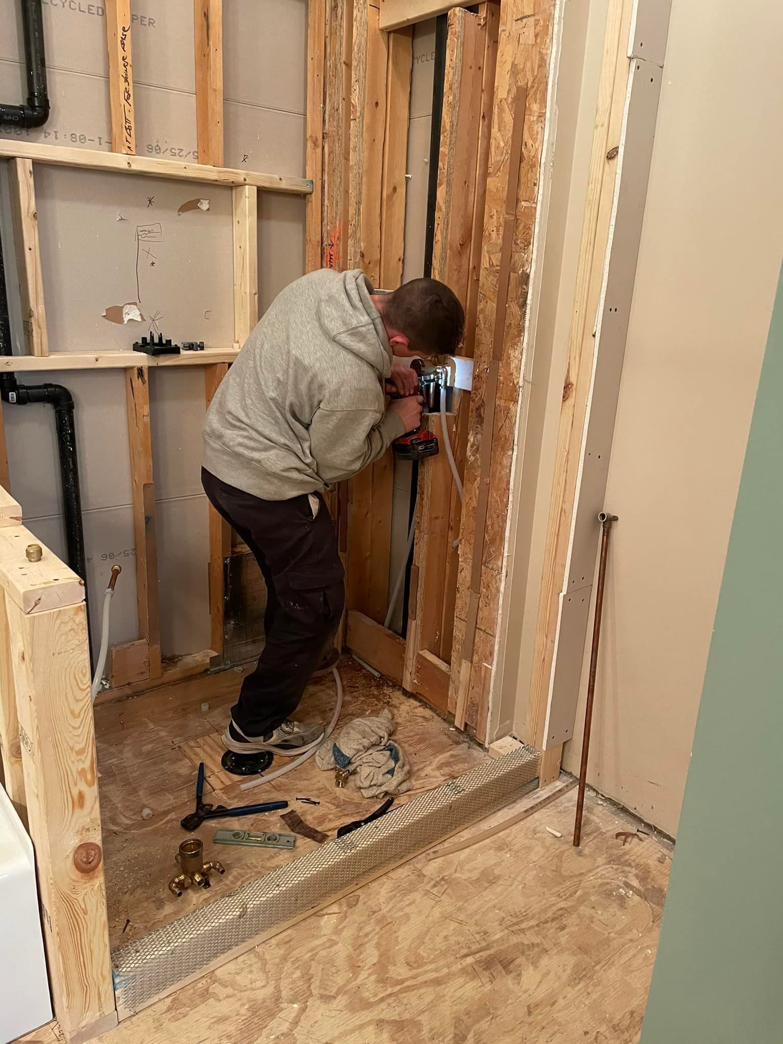 A man is working on a wooden wall with a drill.
