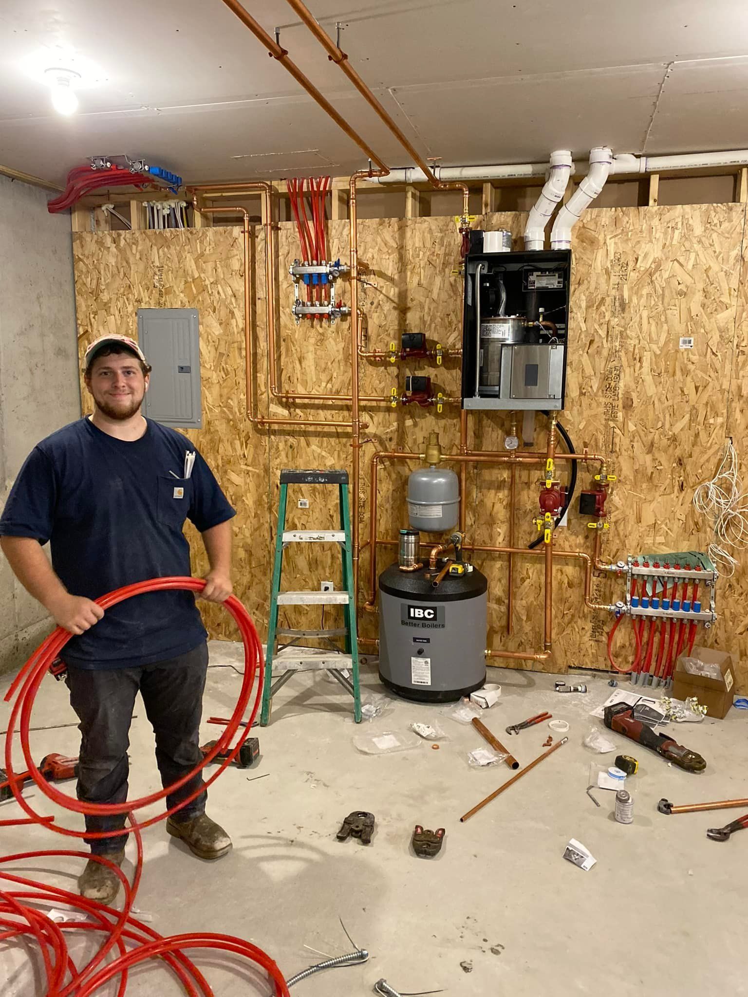 A man is standing in a room holding a red pipe.