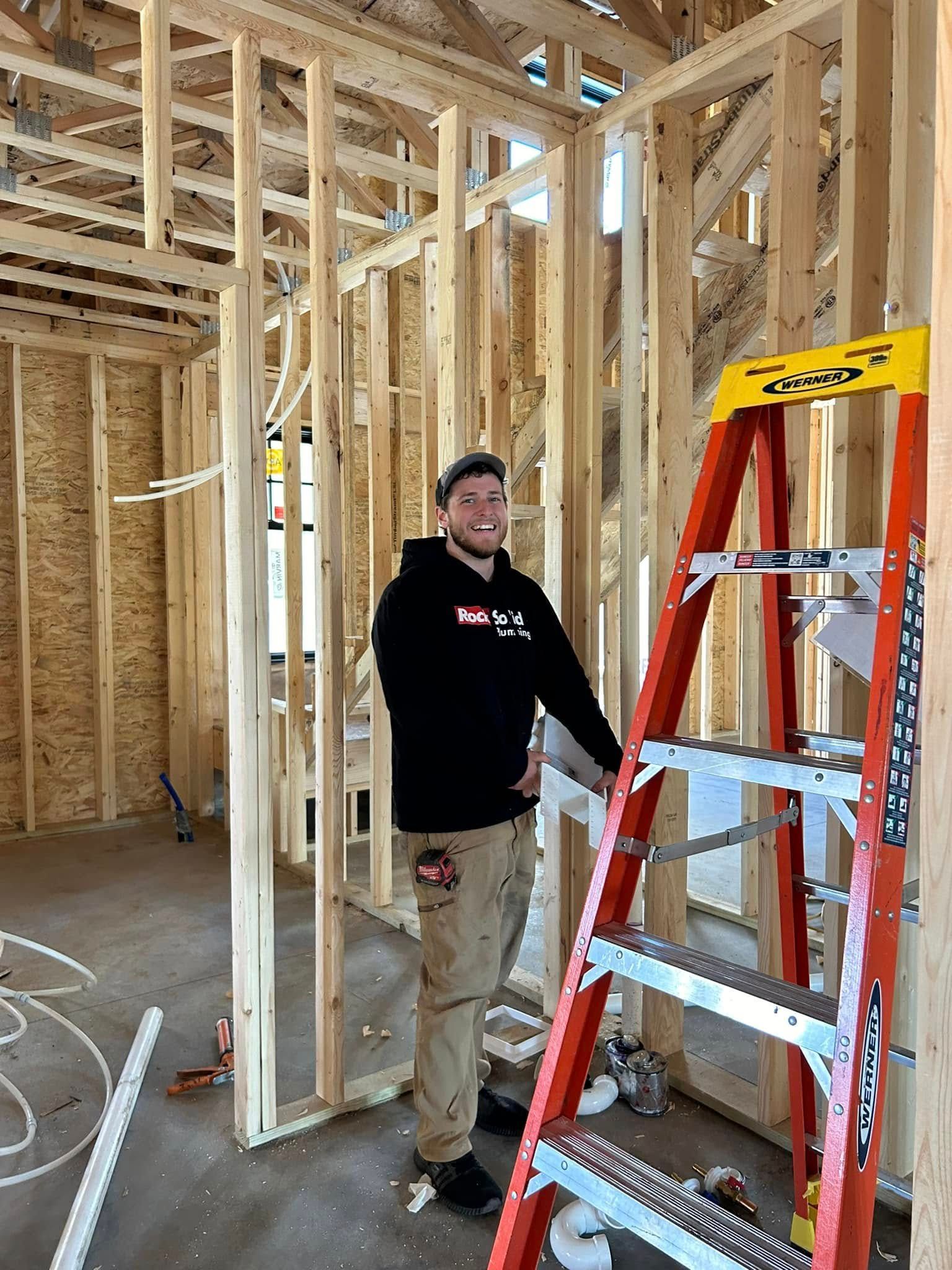 A man is standing next to a ladder in a house under construction.