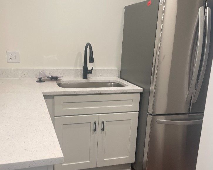 A kitchen with a sink and a stainless steel refrigerator