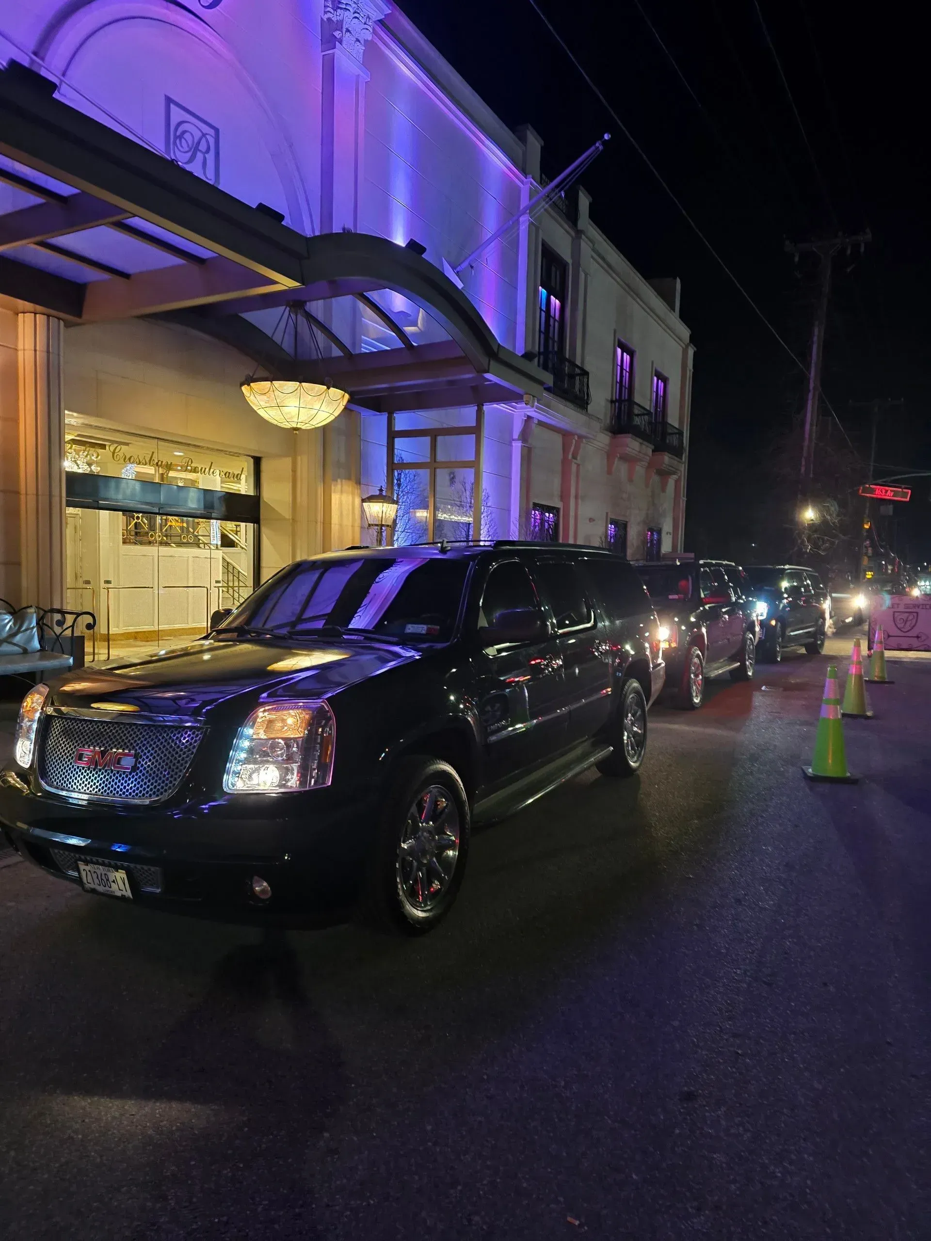 A black suv is parked in front of a building at night