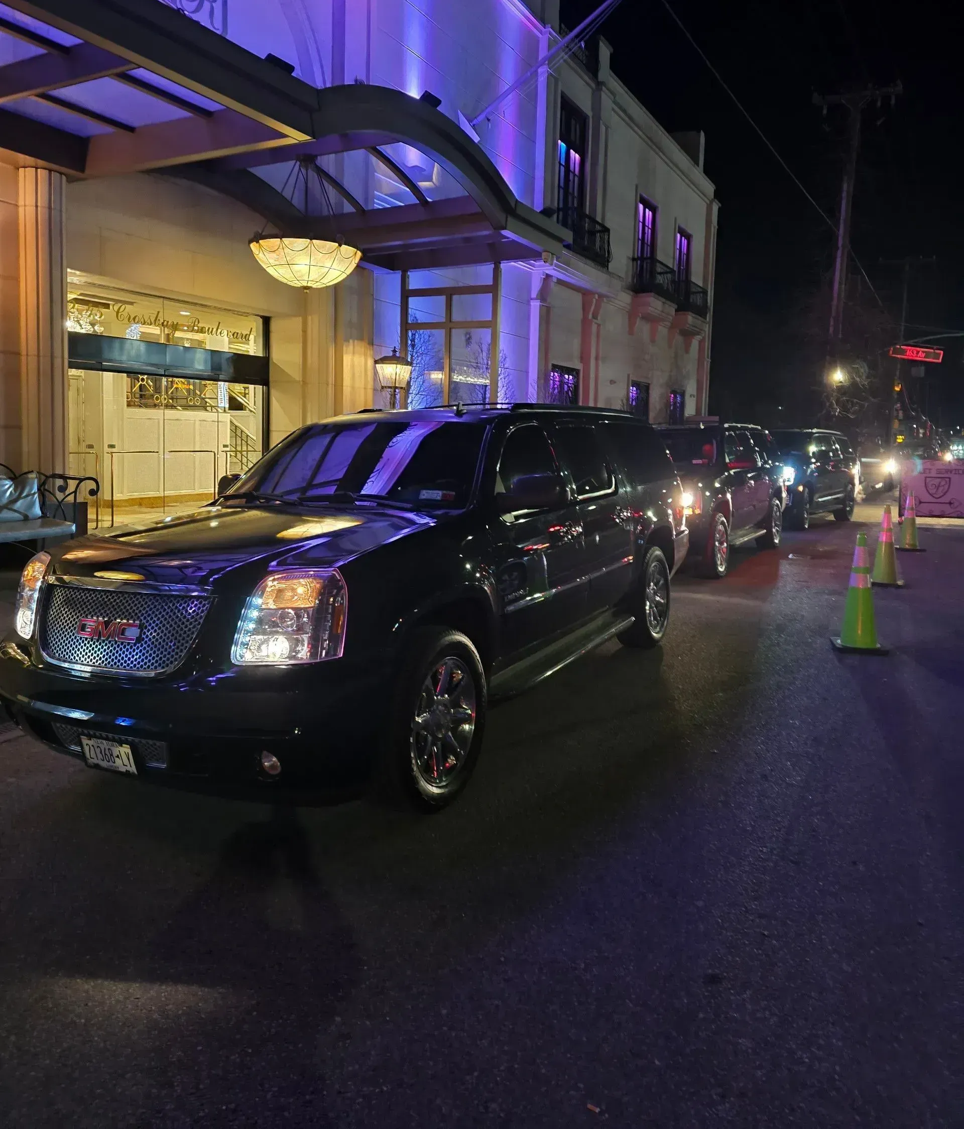 A black suv is parked in front of a building at night