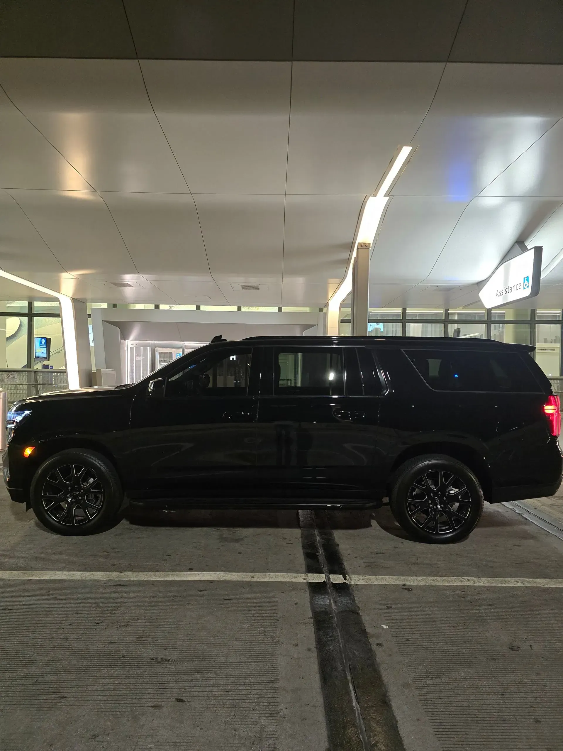 A black SUV is parked in a parking lot at night.