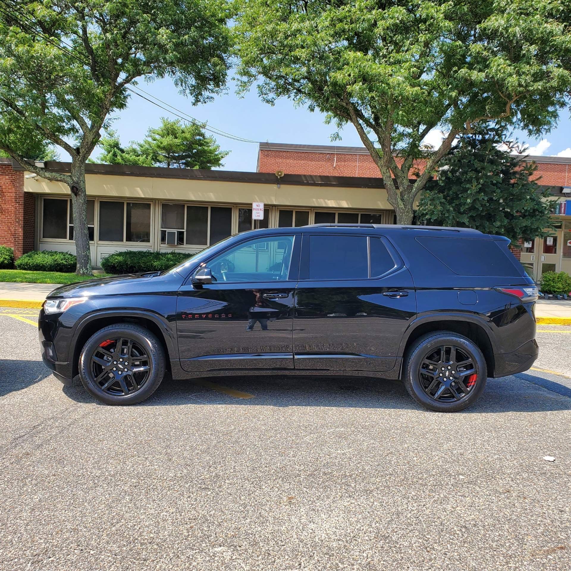 A black SUV is parked in a parking lot in front of a building.