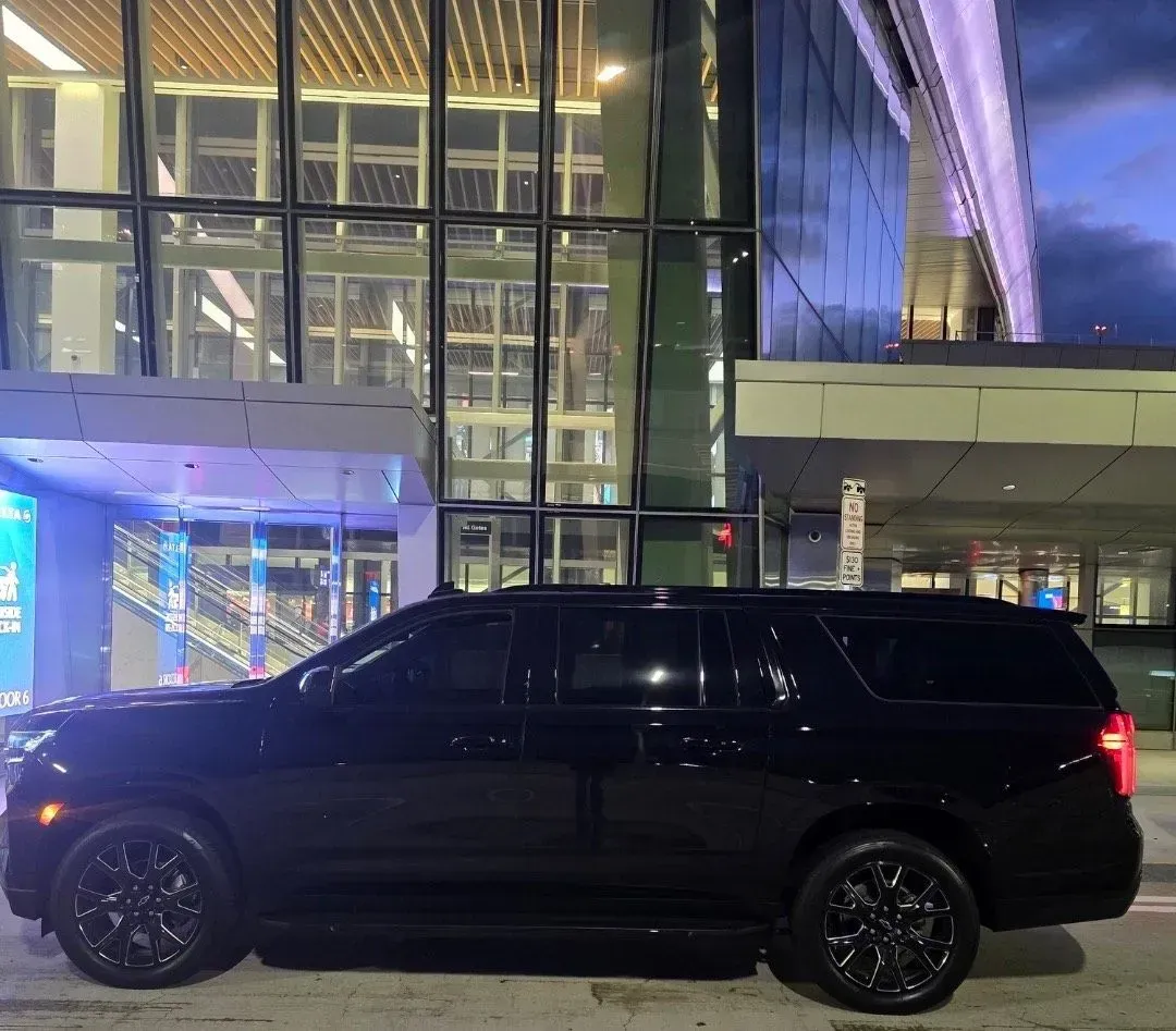 A black SUV is parked in front of a building at night.