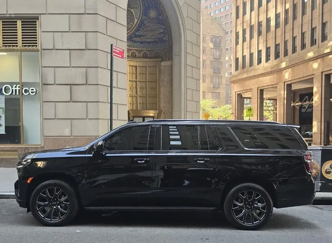 A black SUV is parked on the side of the road in front of a building.