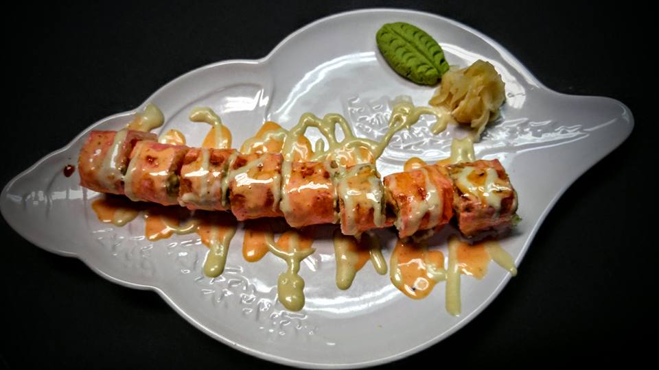 A white plate topped with sushi and pickles on a black background.