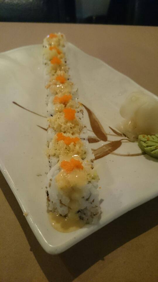 A row of sushi rolls on a white plate on a table.