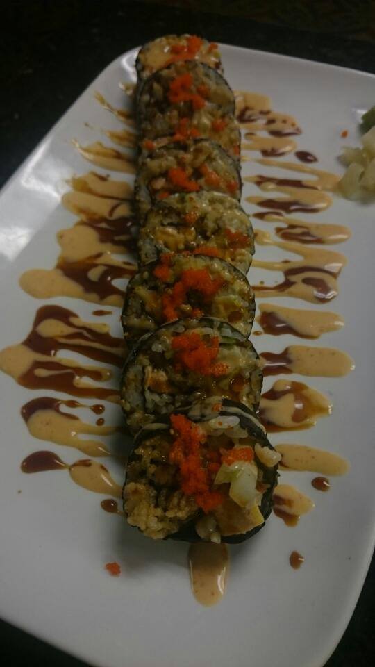 A white plate topped with a sushi roll and sauce.