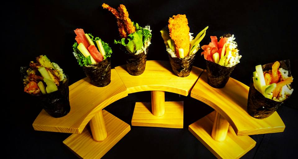 A bunch of different types of sushi on a wooden display