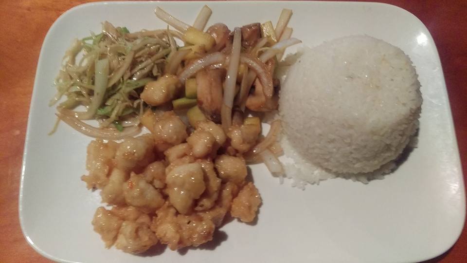 A white plate topped with rice , chicken , and vegetables.